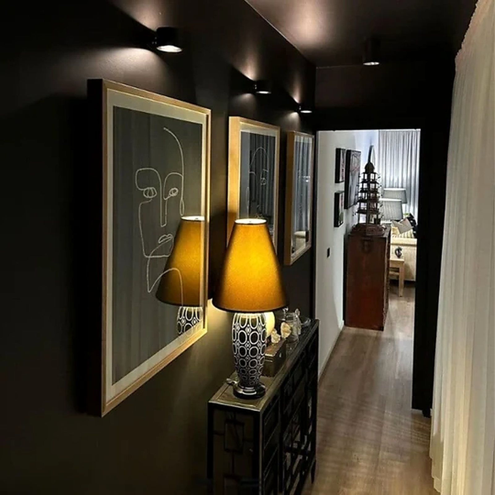 Battery operated wall sconces lighting a dark hallway gallery wall