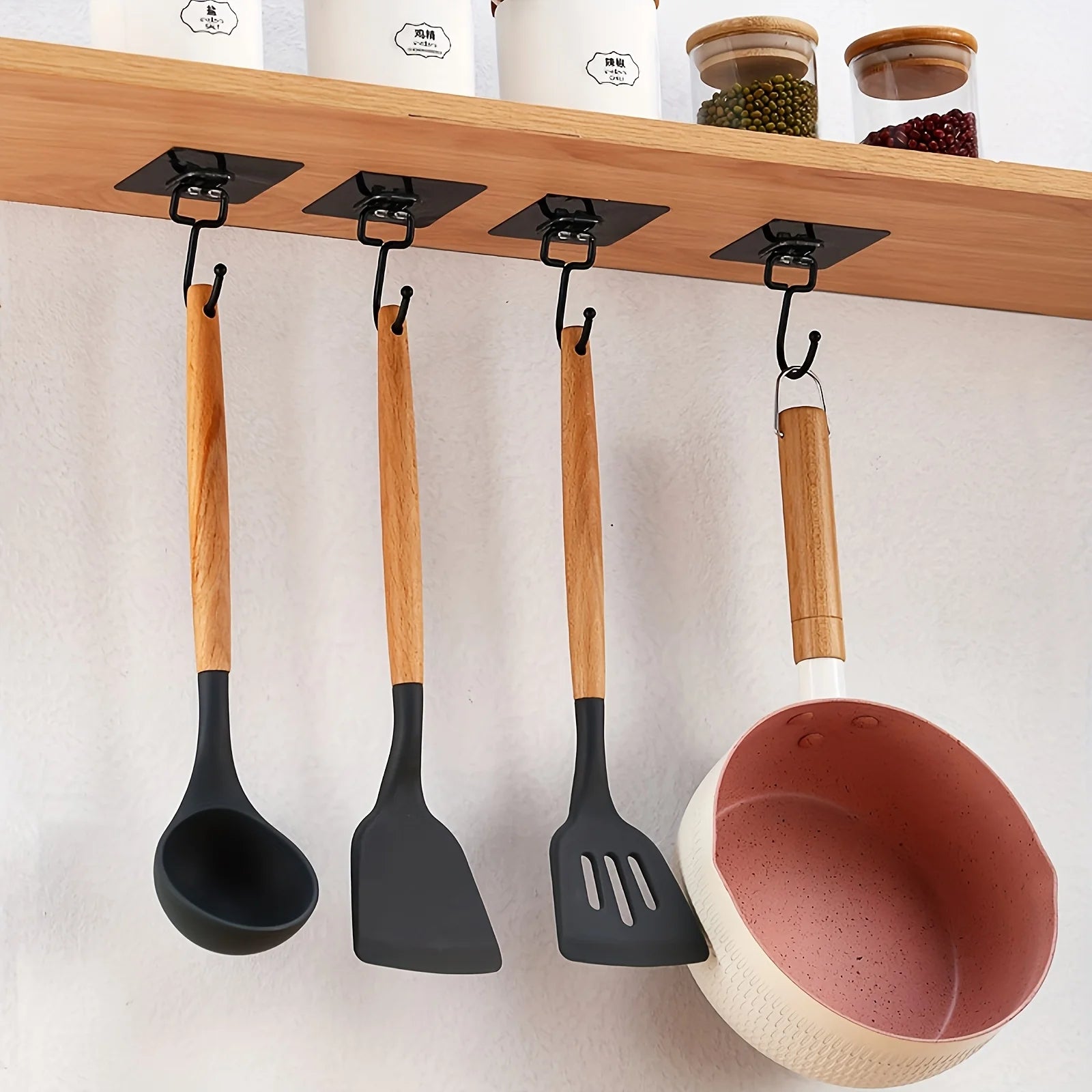 Adhesive wall hooks holding kitchen utensils and a bowl